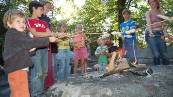 A group of people around a campfire with a rock in the foreground.