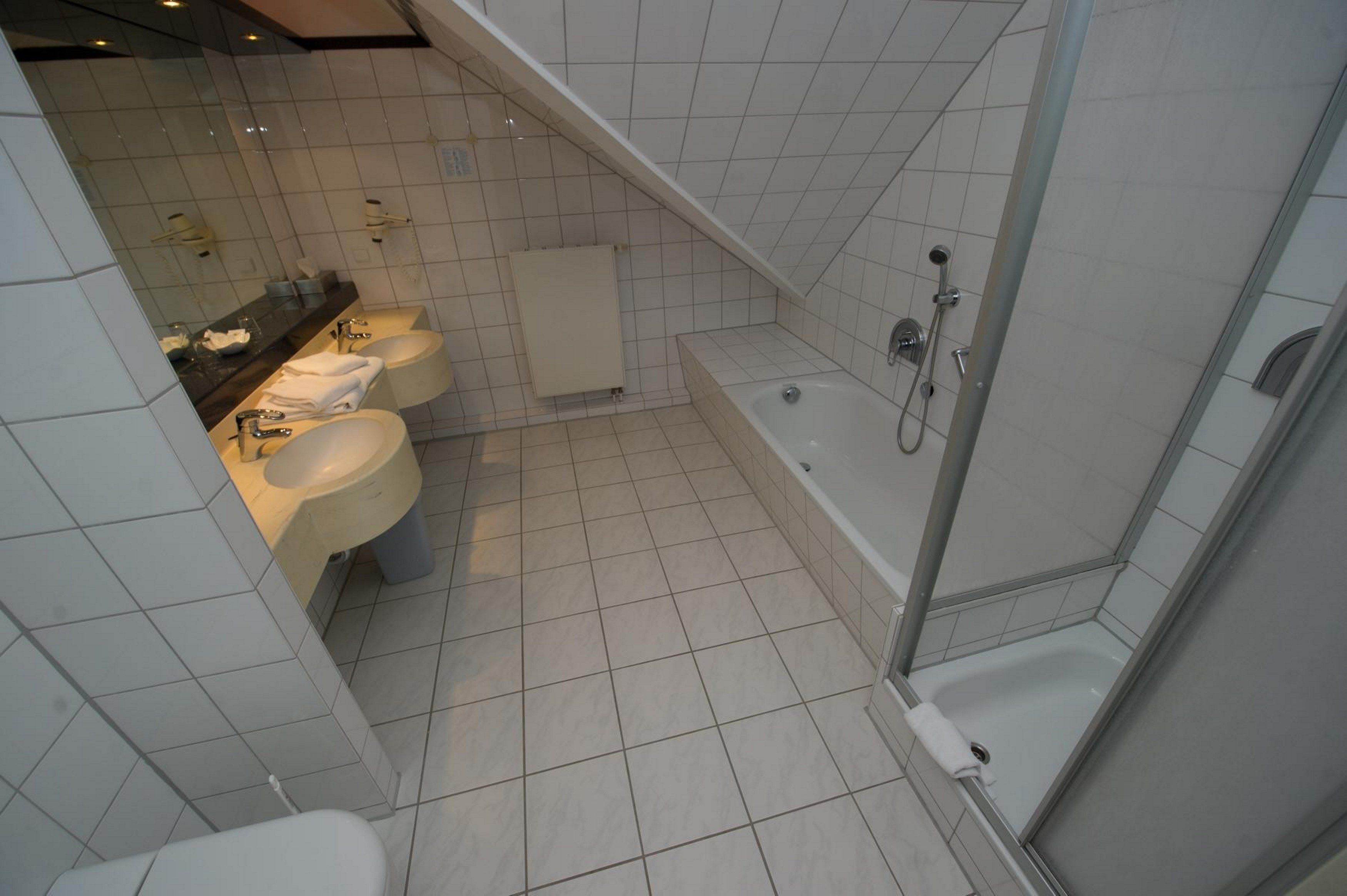 Une salle de bain moderne avec trois lavabos, une baignoire et une douche.