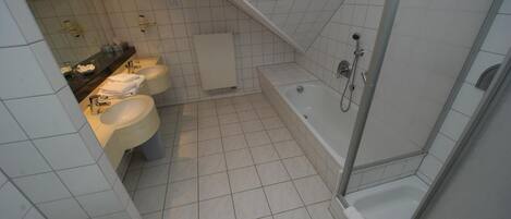 Une salle de bain moderne avec trois lavabos, une baignoire et une douche.