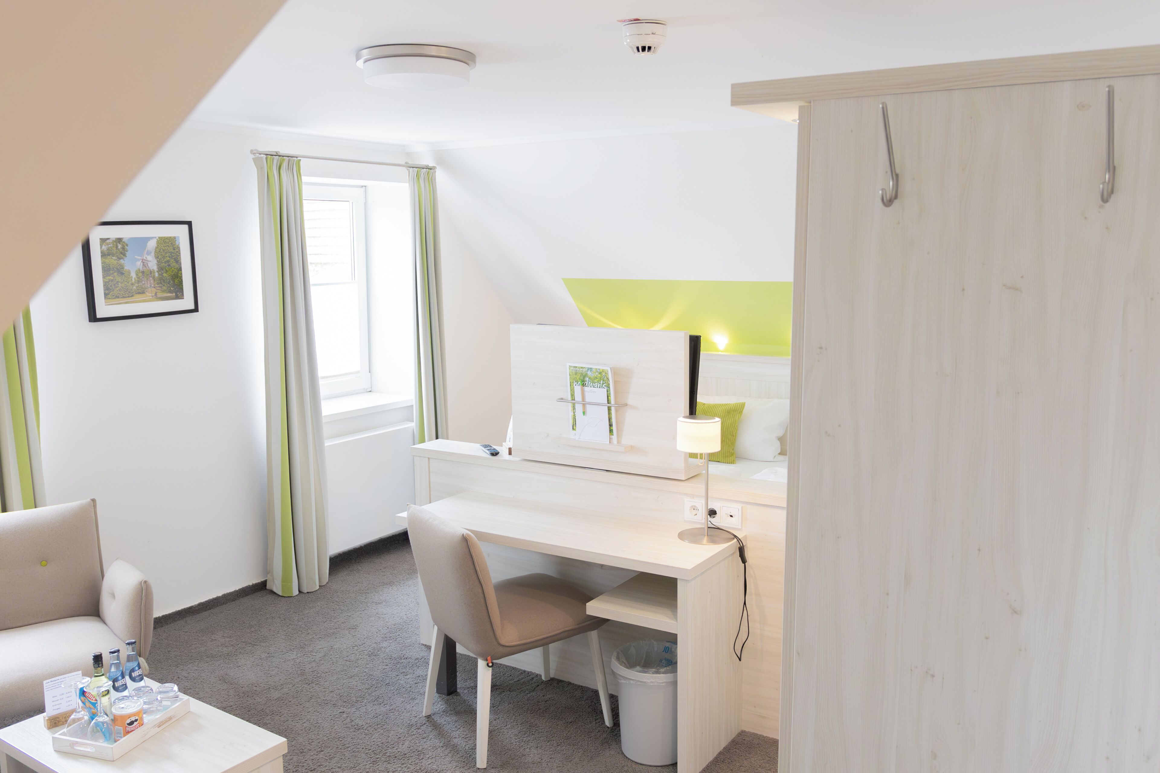 Et værelse med skrivebord, stol og et lille bord med toiletartikler.