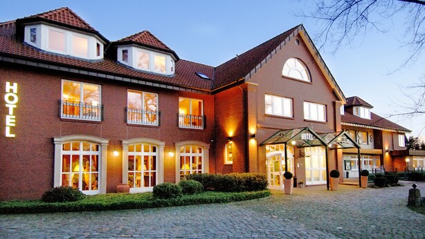 Een hotel met een gevel van baksteen, meerdere ramen en een goed verlichte entree.