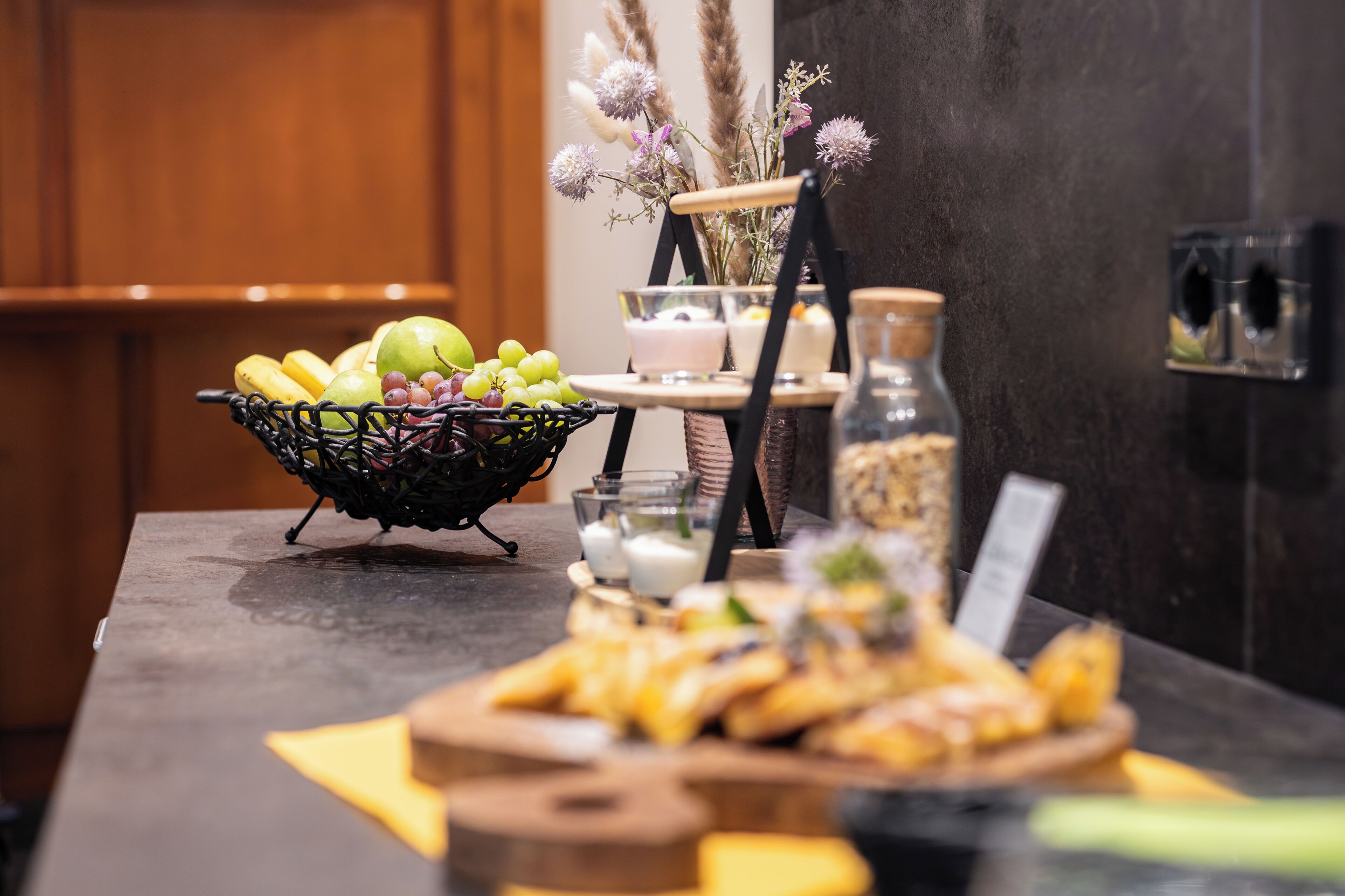 A buffet table with a fruit basket, bowls of soup, and a variety of snacks.