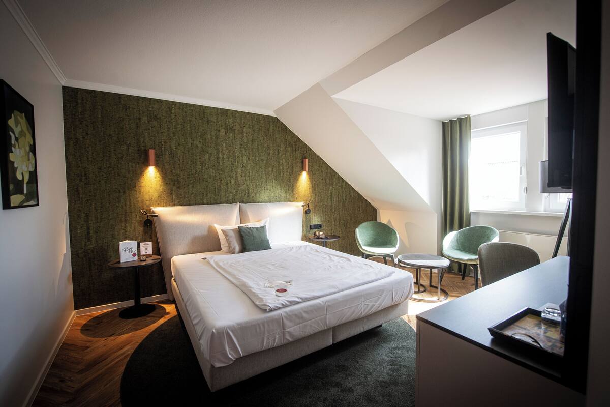 A modern hotel room with a large bed, two bedside tables, a desk, and a chair.