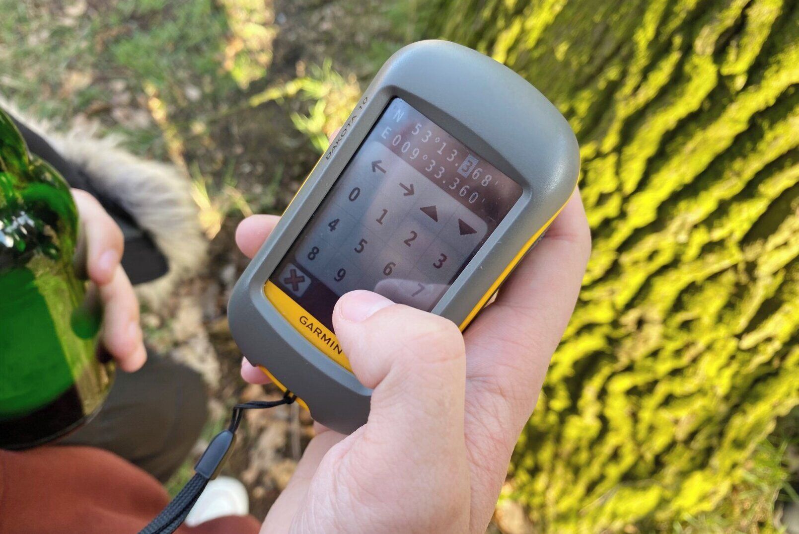 A person holding a Garmin GPS device outdoors.