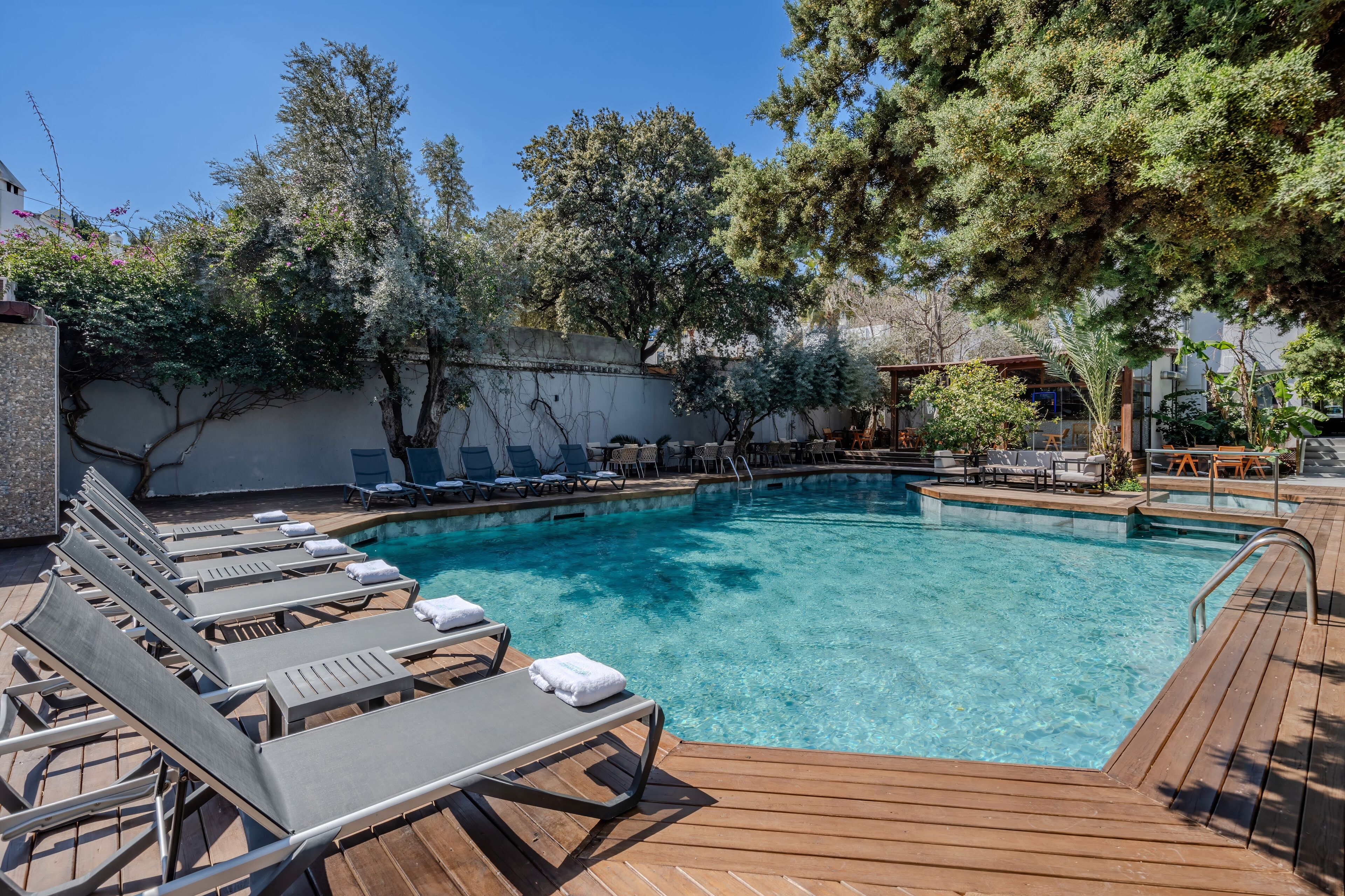 A pool area with lounge chairs and a wooden deck.