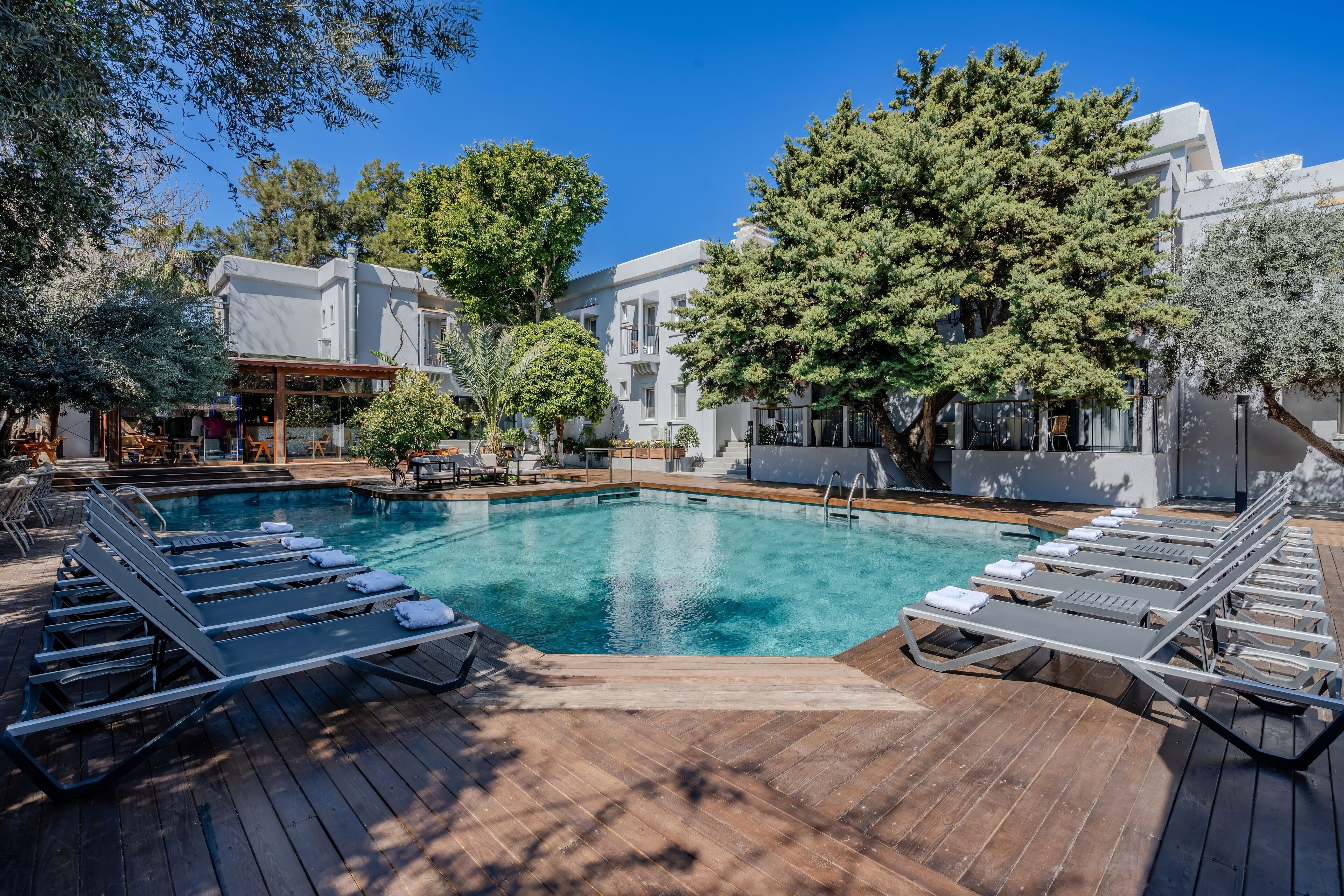 Piscina com espreguiçadeiras e um deck de madeira.