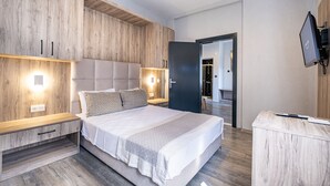 A modern bedroom with a large bed, wooden headboard, bedside tables, and a TV mounted on the wall.