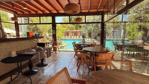 A wooden deck with outdoor seating, a pool, and a view of the surrounding greenery.