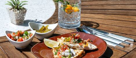 A wooden table with a plate of food, a glass of drink, and a small plant.