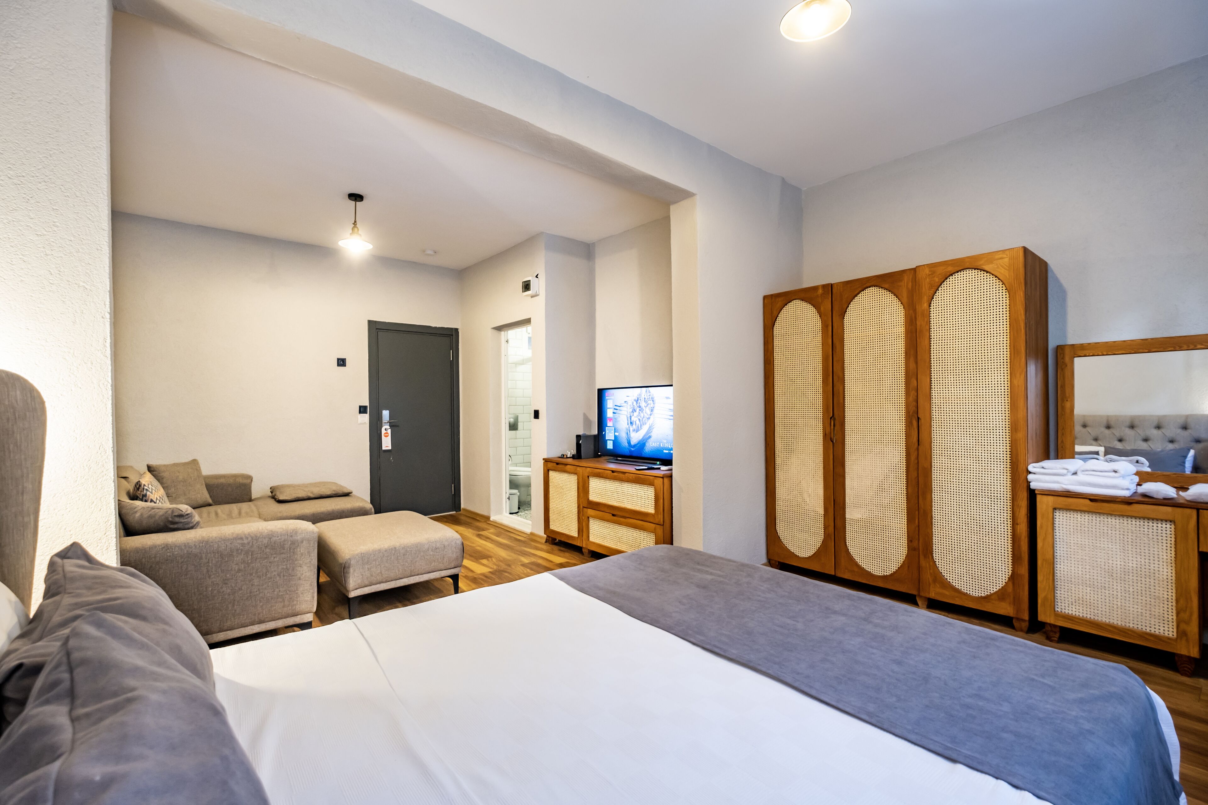 A hotel room with a bed, a sofa, a TV, and a wardrobe.