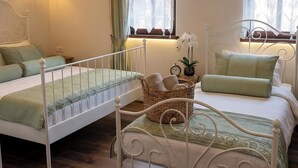 Un dormitorio con dos camas, una mesita de noche, una lámpara, una ventana con cortinas y un equipo de aire acondicionado.