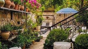 Un patio con una mesa de vidrio, sillas y una botella de vino.