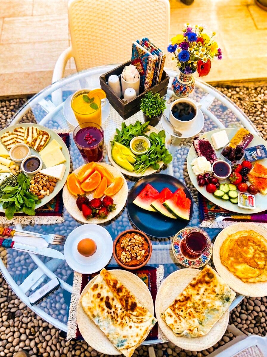 A round table with a variety of food items, including fruits, vegetables, and flatbreads, arranged for a meal.