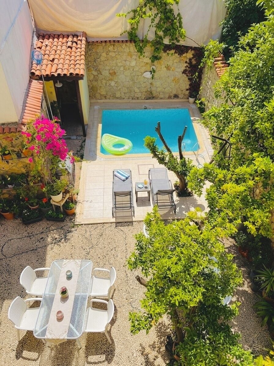 A rooftop pool with a stone wall, a covered patio, and outdoor seating.