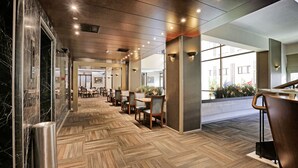 A modern hotel lobby with a herringbone patterned floor, wooden chairs, and tables. - Kaya Prestige (Izmir)
