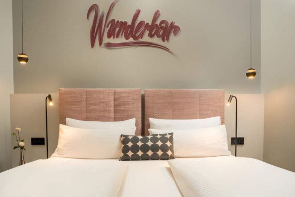 A double bed with a headboard, two bedside lamps, and a pillow with a geometric pattern.
