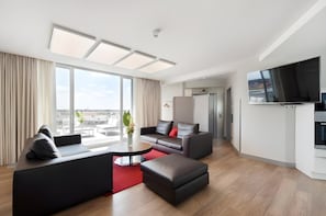 A modern living room with a sofa, ottoman, and a flat-screen TV. - City Aparthotel Muenchen (Muenchen)