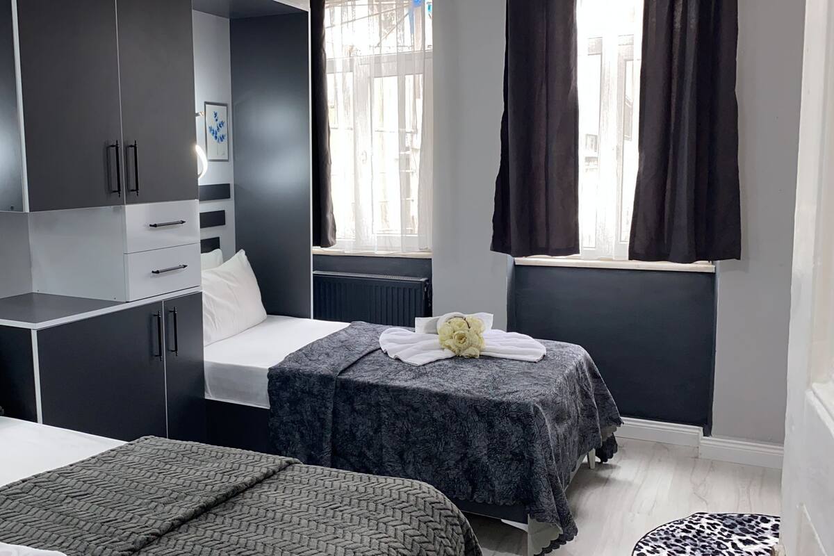 A modern bedroom with a bed, a desk, and a window with curtains.