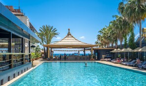 A swimming pool with lounge chairs and umbrellas, a covered seating area, and palm trees. - Ananea Kleopatra Beach (+12 Adults Only) (Alanya)