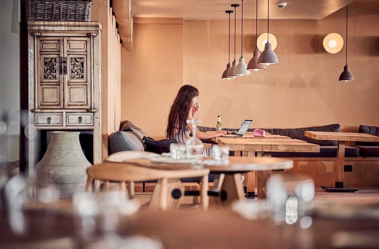 A cozy cafe interior with wooden furniture, pendant lighting, and a vintage cabinet.