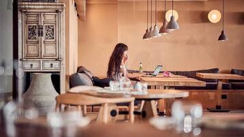 A cozy cafe interior with wooden furniture, pendant lighting, and a vintage cabinet.