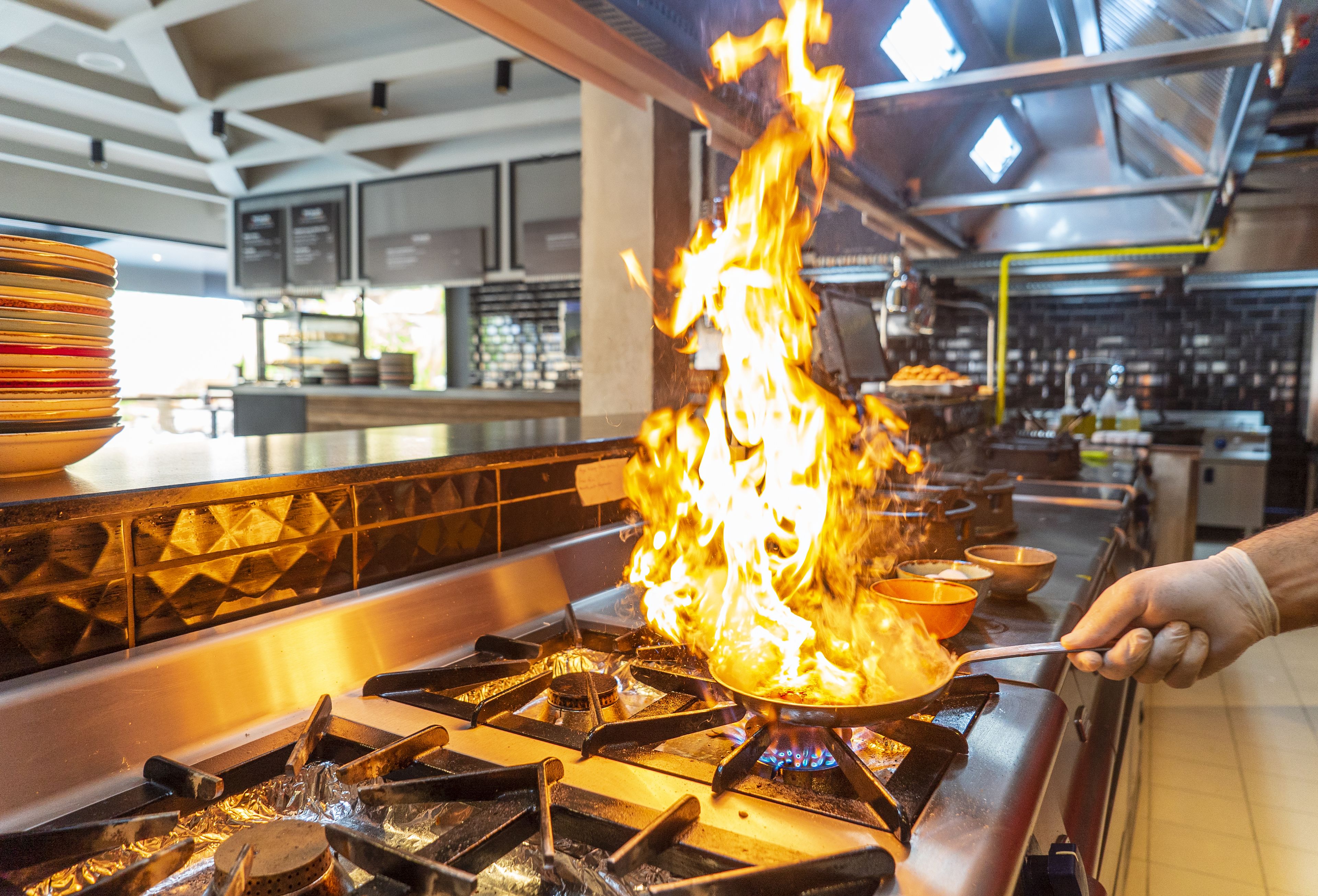 A kitchen with a gas stove and a pot on fire.