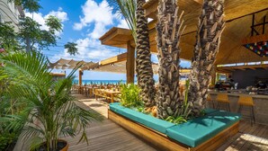 Een terras buiten met houten vloer, zitgedeeltes en een bar.