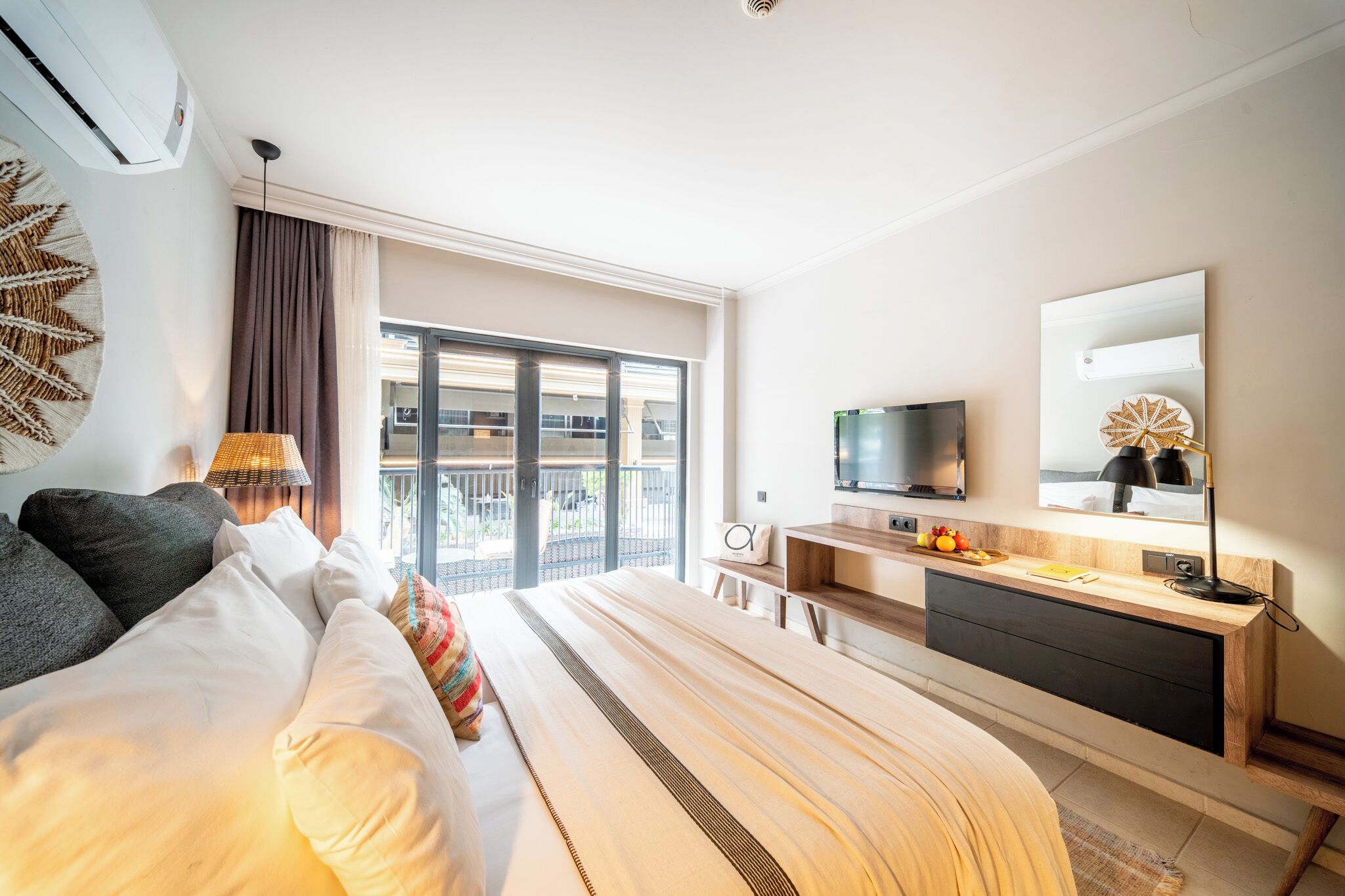 Ein modernes Hotelzimmer mit einem großen Bett, einem Schreibtisch, einem Fernseher und einem Balkon mit Aussicht.