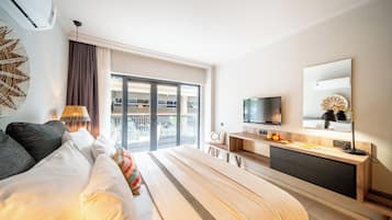 Ein modernes Hotelzimmer mit einem großen Bett, einem Schreibtisch, einem Fernseher und einem Balkon mit Aussicht.