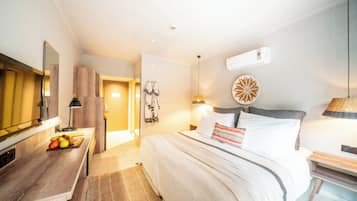 A hotel room with a bed, bedside table, lamp, and a wall-mounted air conditioning unit.