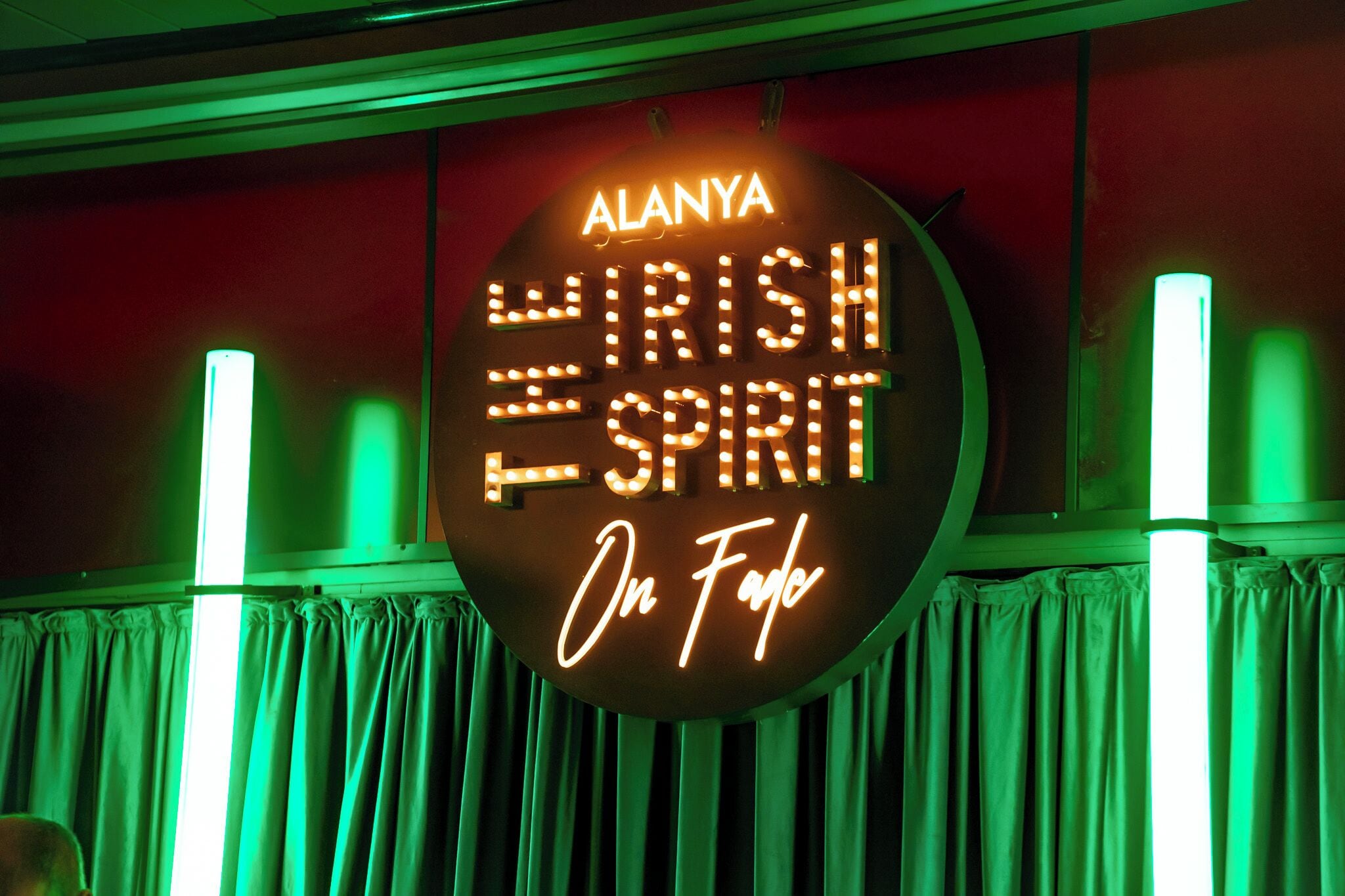 Un letrero de neón con el texto 'ALANYA WISH SPIRIT On Fuego' sobre un fondo rojo.