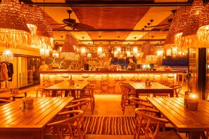 A restaurant with wooden tables and chairs, hanging light fixtures, and a bar area. - Ananea Kleopatra Beach (+12 Adults Only) (Alanya)