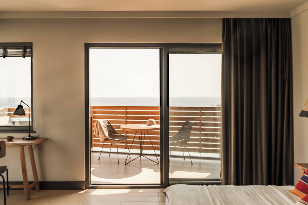 A hotel room with a balcony, a desk, and a bed.