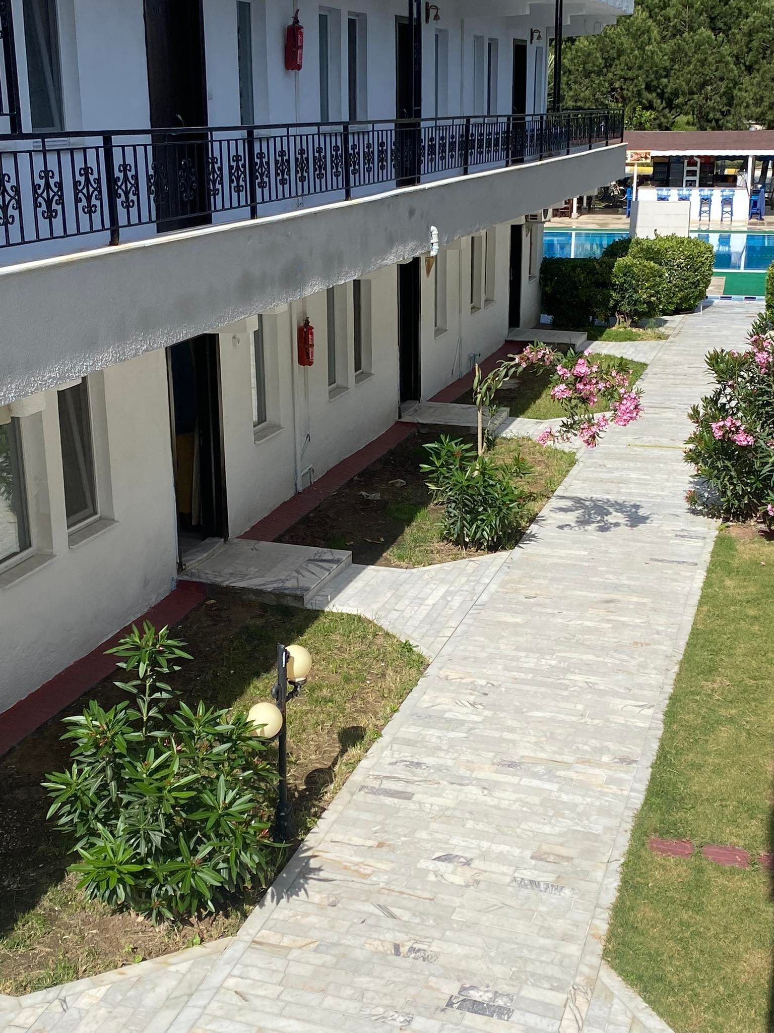 A hotel with a covered outdoor area, a swimming pool, and a garden with plants and flowers.