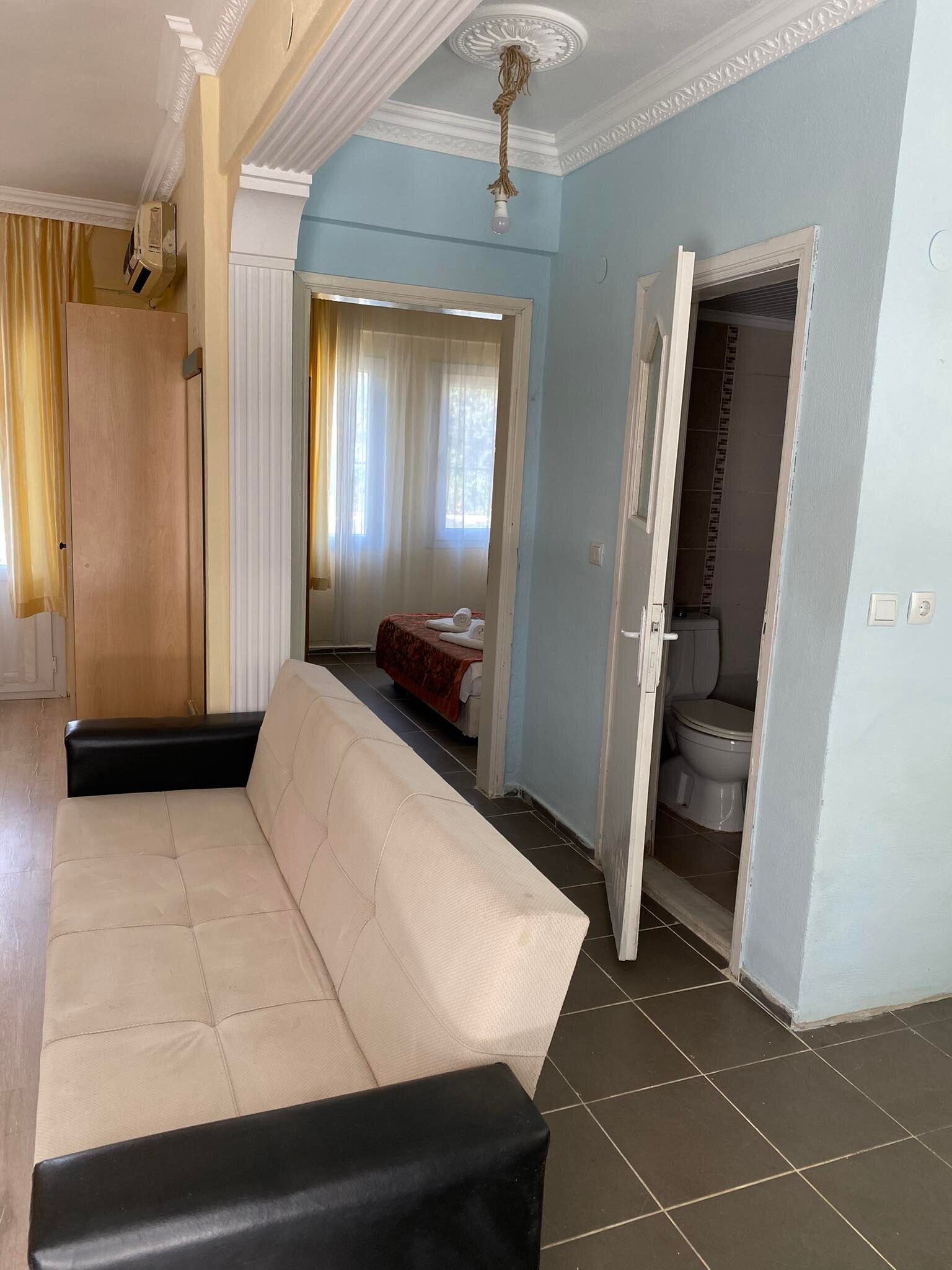 Una habitación con sofá, cama, baño y un pasillo.