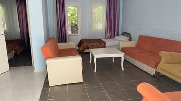 Une pièce comprenant deux canapés, une petite table et un lit recouvert d’une couvre-lit à motifs.