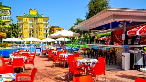 A poolside area with red chairs and tables, umbrellas, and a bar area with a sign reading "ALGiDA". - Ark Suite Hotel (Alanya)