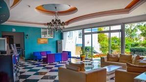 A hotel lobby with a checkered floor, a chandelier, and a large window with a view of greenery and buildings. - Ark Suite Hotel (Alanya)