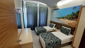 A hotel room with two beds, a desk, and a large beach mural on the wall. - Ark Suite Hotel (Alanya)