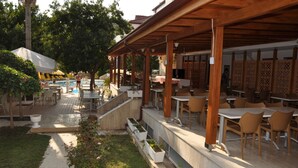 An outdoor patio area with tables and chairs, a pool, and a covered seating area.