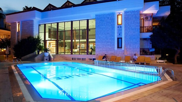 A modern hotel with a swimming pool, large windows, and a brick facade.
