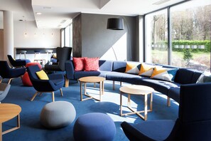 A modern lounge area with a blue carpet, a large sectional sofa, and multiple chairs.