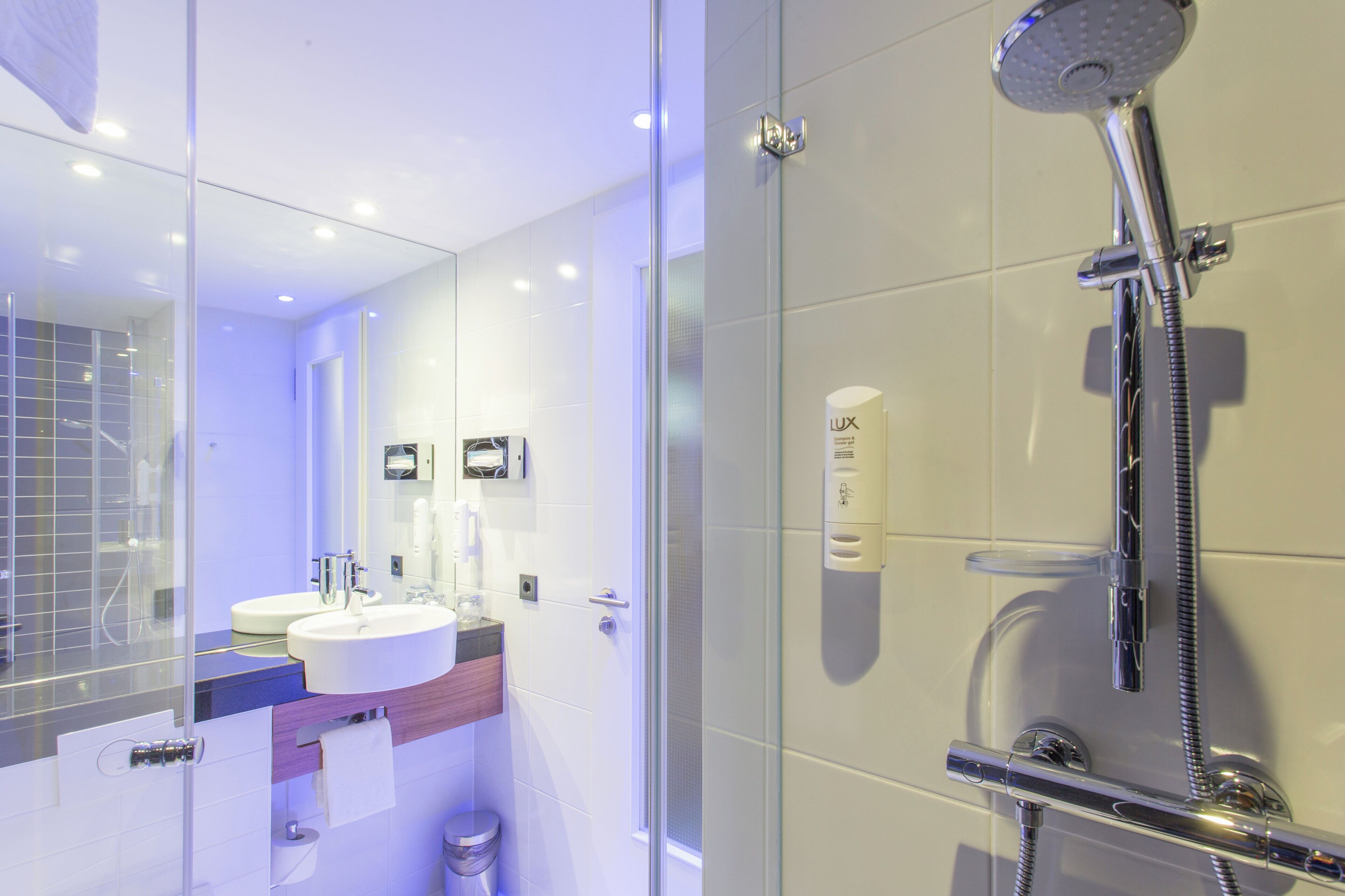 A modern bathroom with a glass-enclosed shower, a sink, and a mirror.