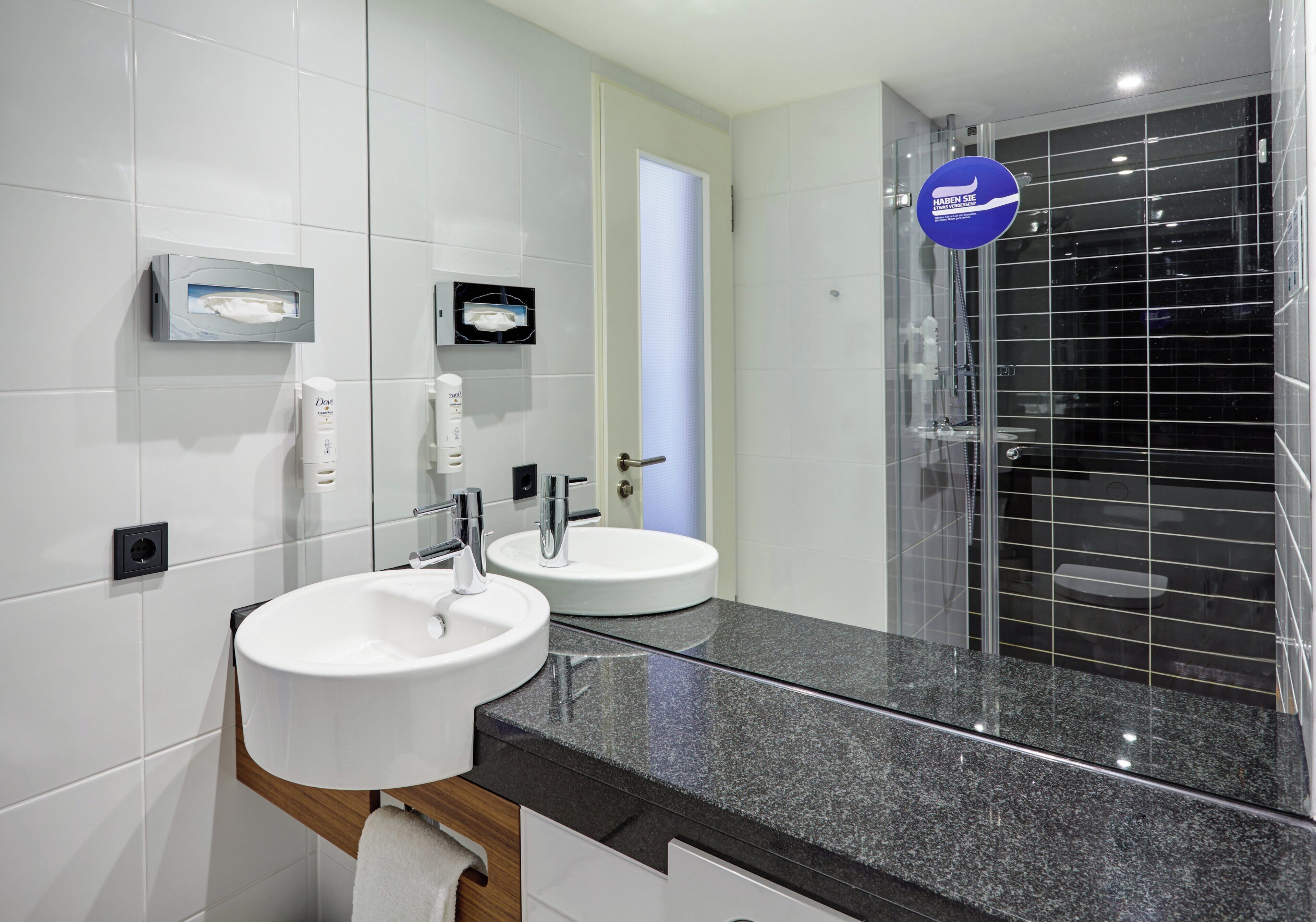 A modern bathroom with two sinks, a mirror, and a glass-enclosed shower.