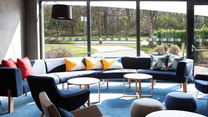 Un área de lounge moderna con un sofá modular, mesas redondas y sillas contemporáneas.