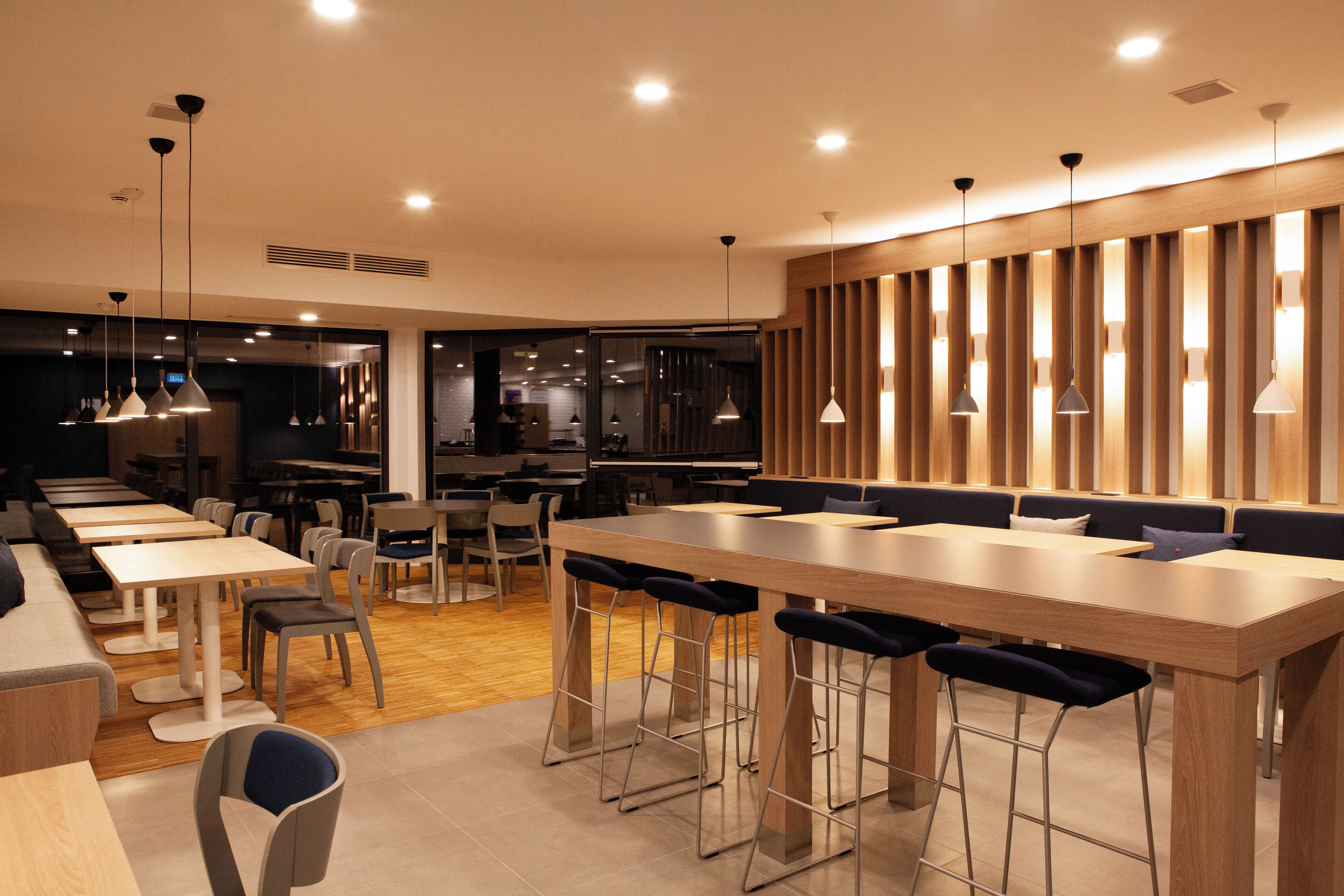 Ein modernes Restaurant mit einer langen Theke, Barhocker und mehreren Sitzbereichen.