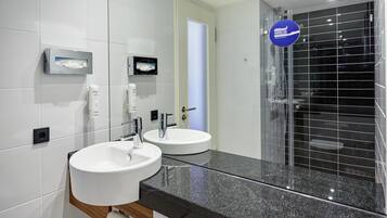 A modern bathroom with two sinks, a large mirror, and a glass shower enclosure.