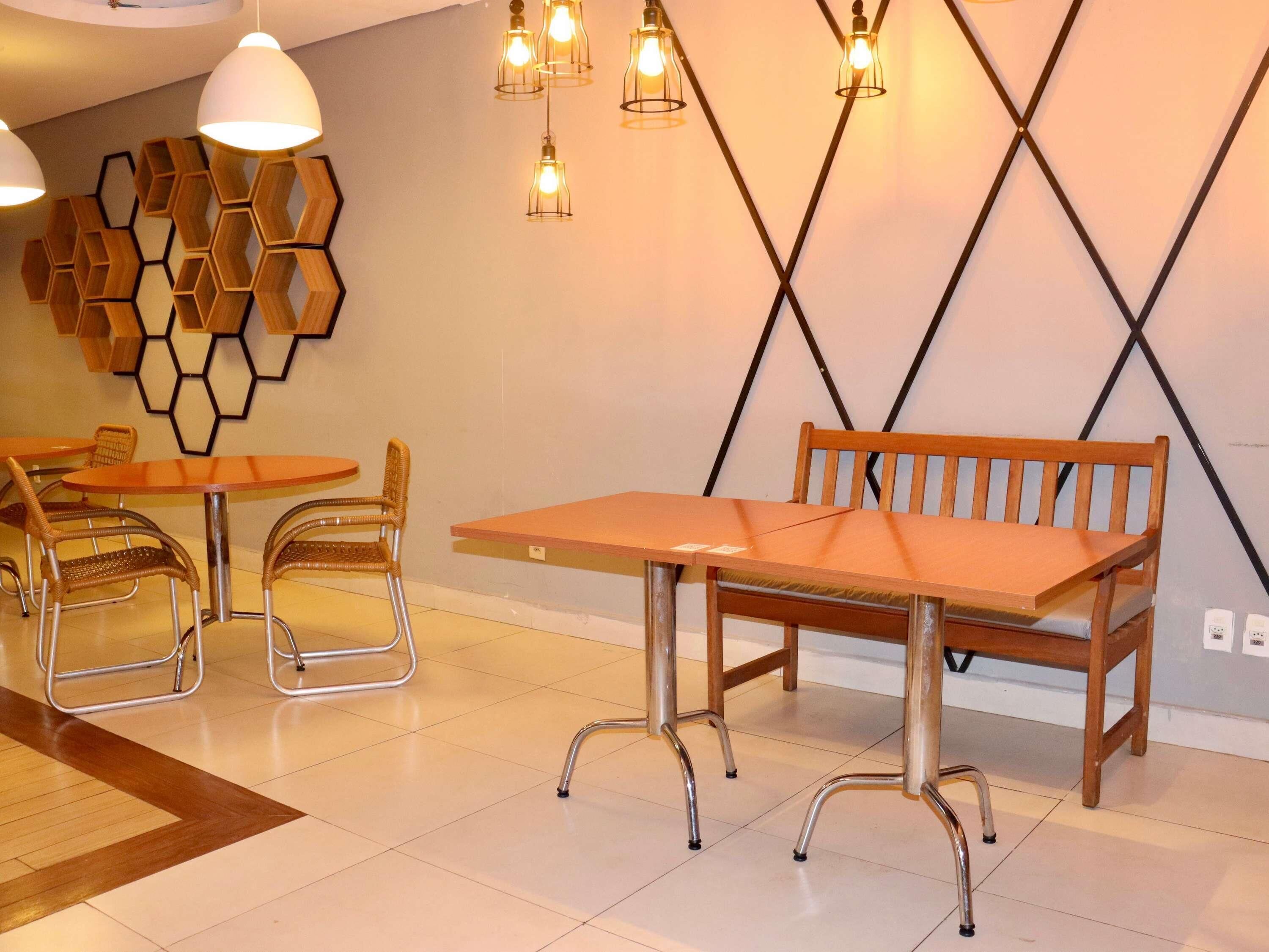 Un comedor moderno con decoración hexagonal en la pared, sillas de estructura metálica y un banco de madera.