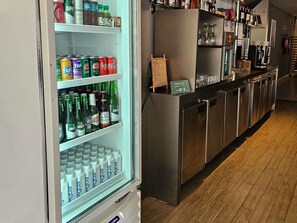 A bar area with a refrigerator stocked with beverages, a counter with glassware, and a wooden floor. - ibis Mossoro (Mossoro)