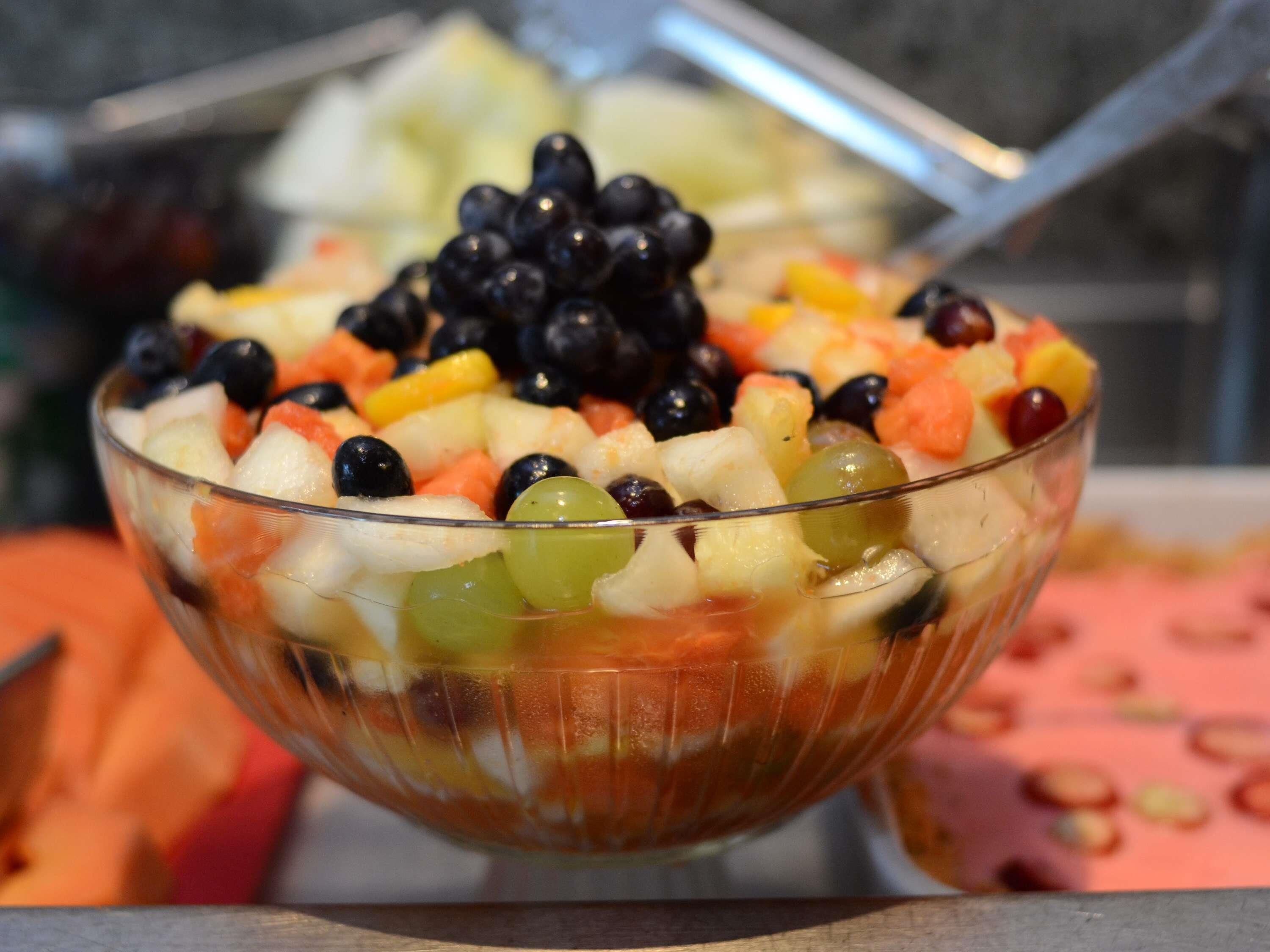 A bowl of fruit salad with various fruits and a spoon.